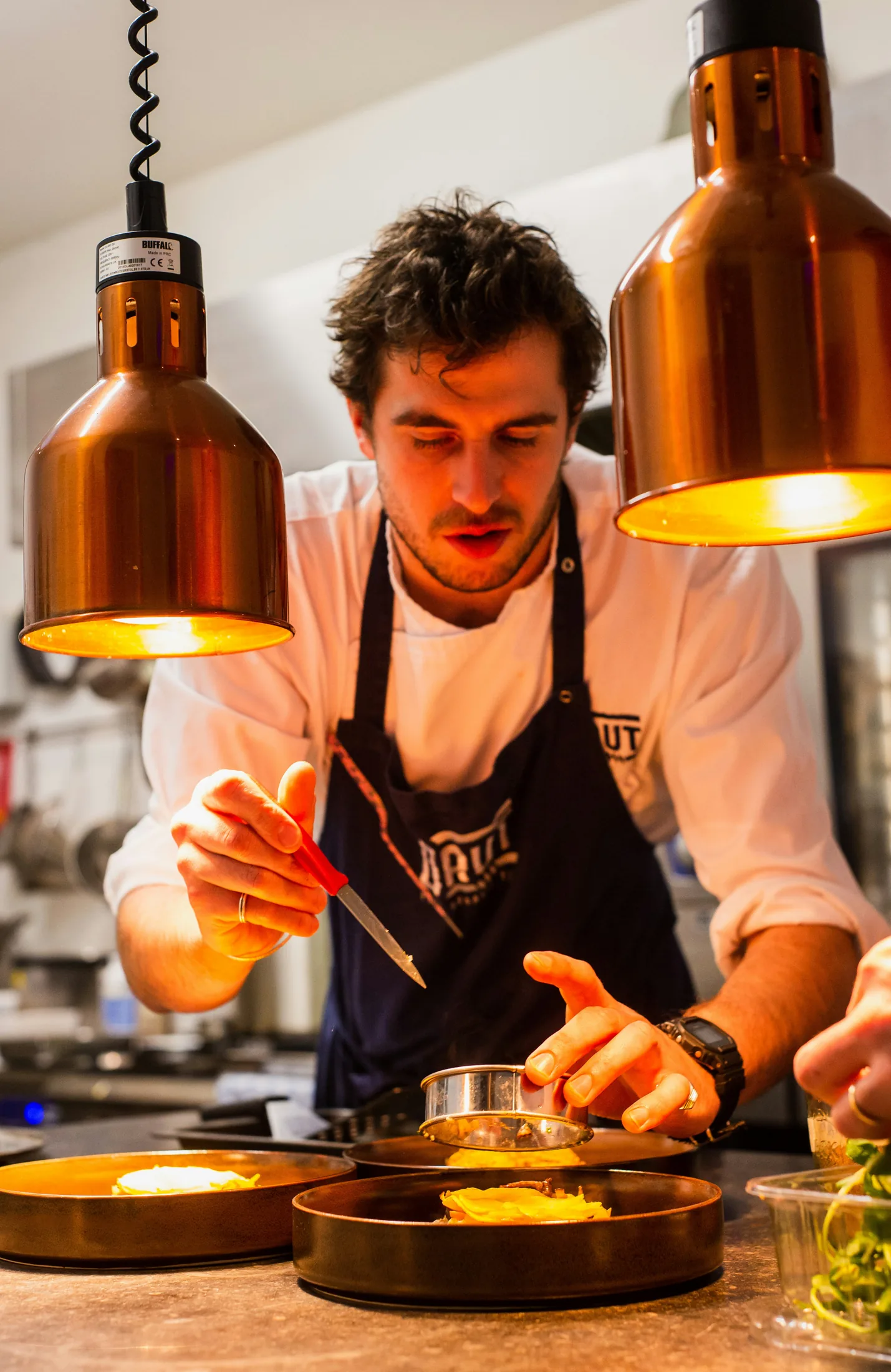 A chef carefully plating dishes in a professional kitchen