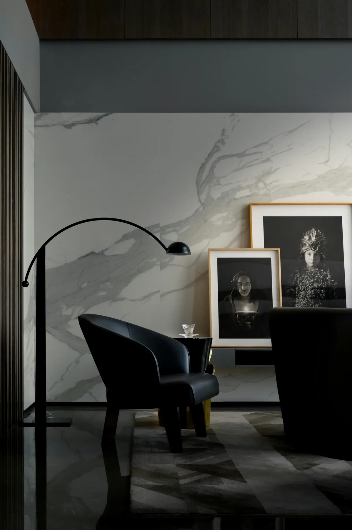 Moody lounge with sculptural black chair and marble wall